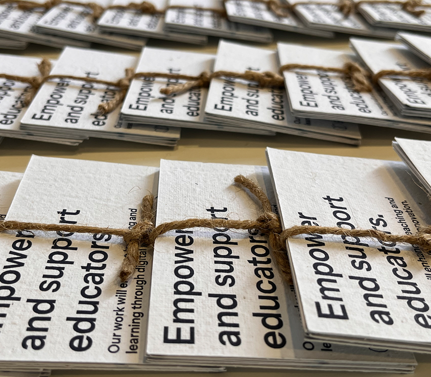 Stacks of small, textured cards tied with twine, each displaying the text "Empower and support educators."